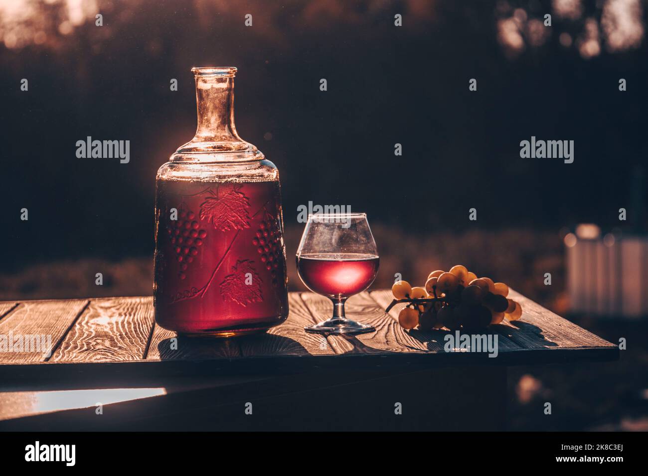 Vino rosso in bicchiere e bottiglia. Sfondo sfocato. Foto Stock