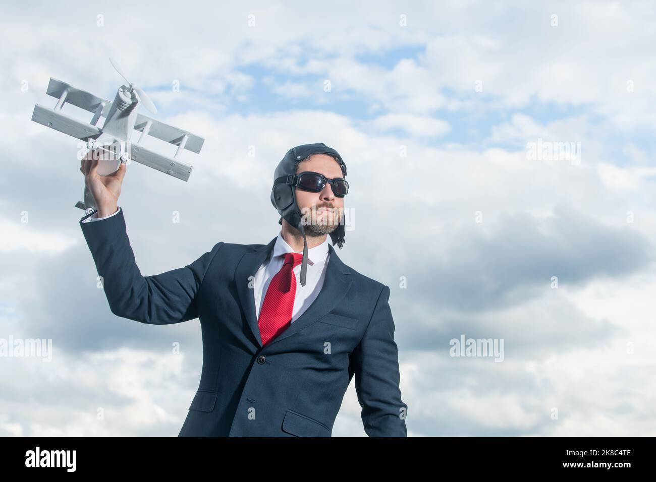 uomo d'affari in tuta e cappello pilota lancio aereo giocattolo. pensare in grande Foto Stock