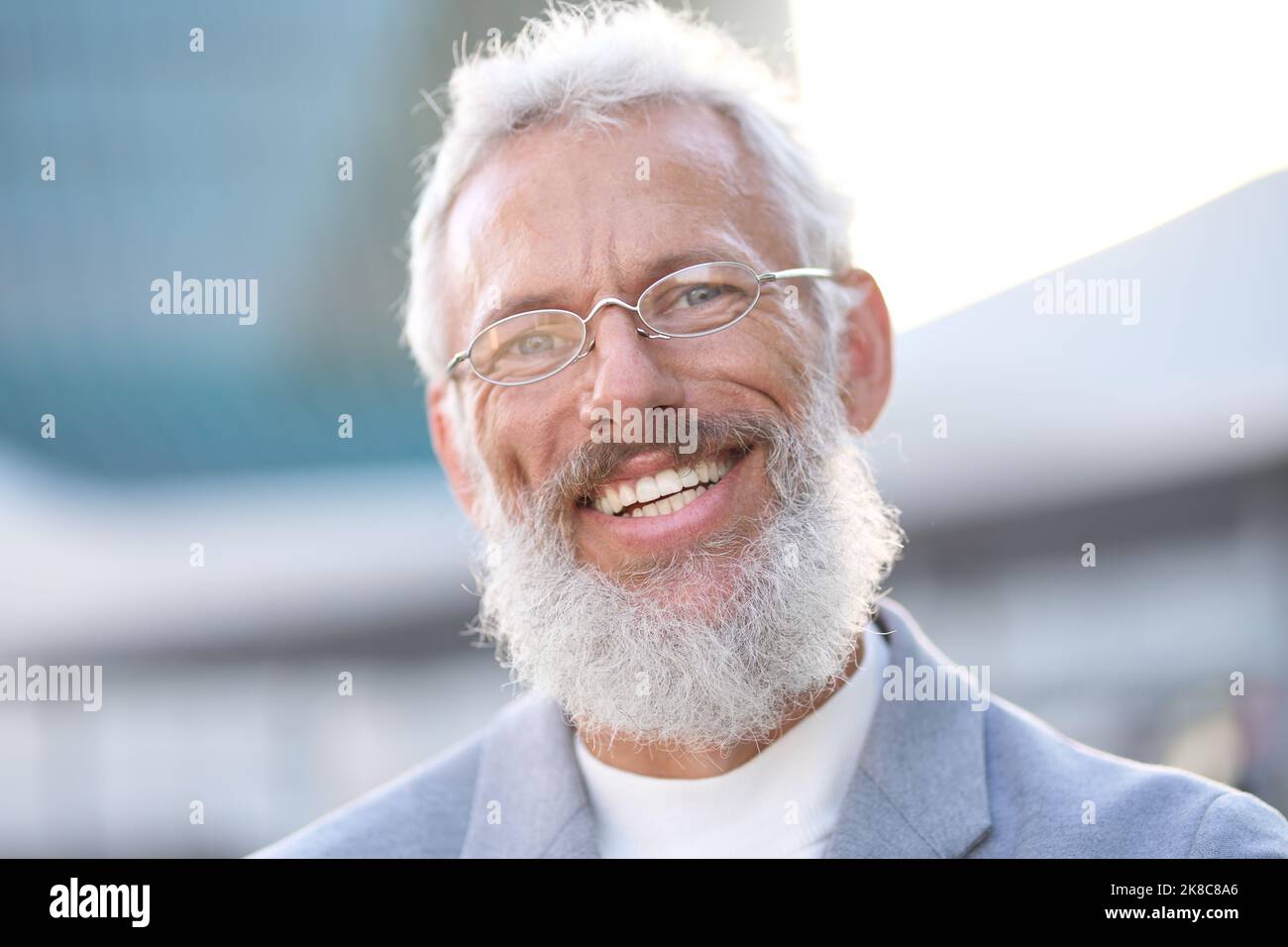 Sorridente uomo d'affari anziano maturo felice in piedi all'aperto, ritratto con foto alla testa. Foto Stock