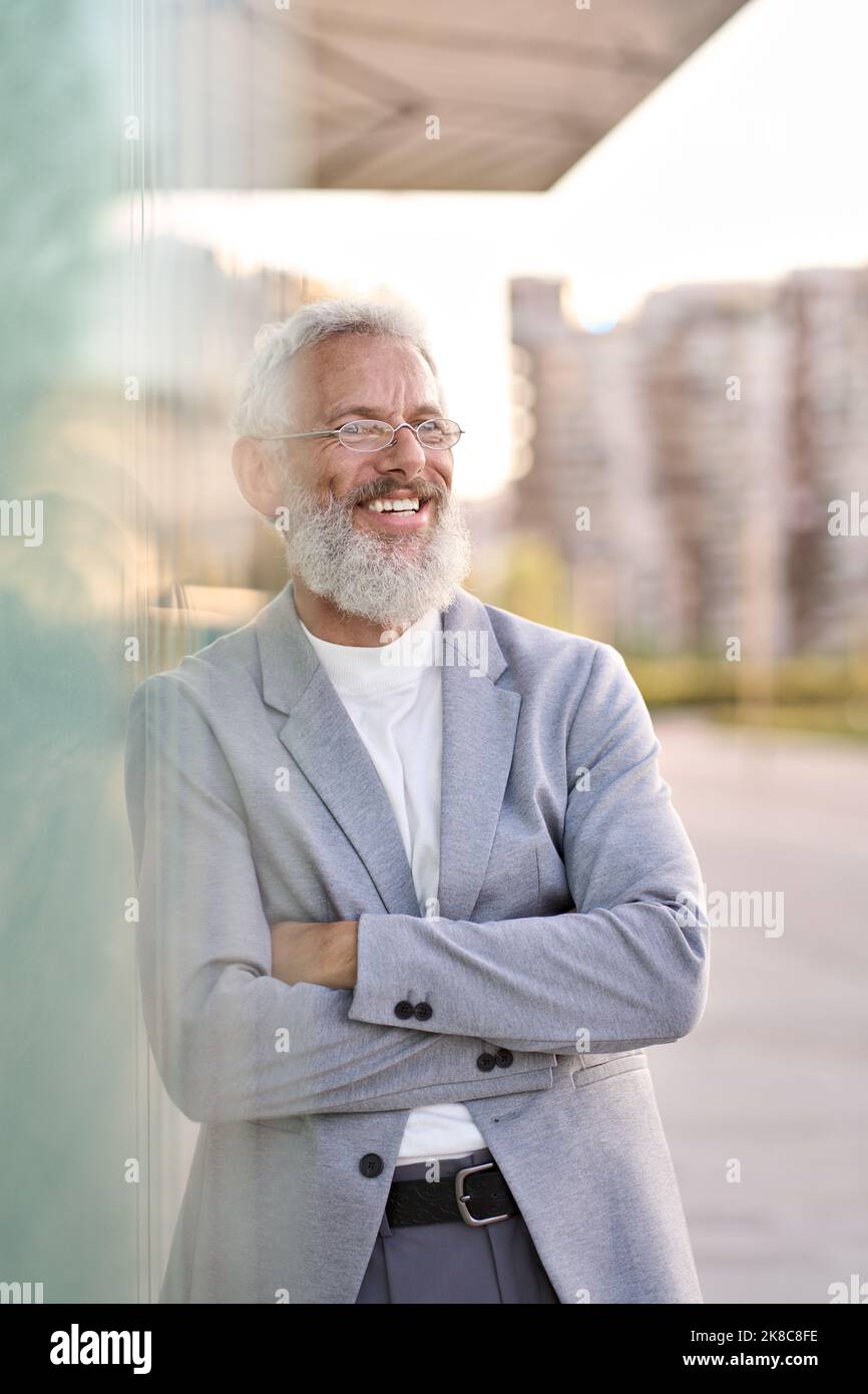 Sorridente uomo d'affari anziano felice che indossa il vestito in piedi all'aperto, ritratto. Foto Stock