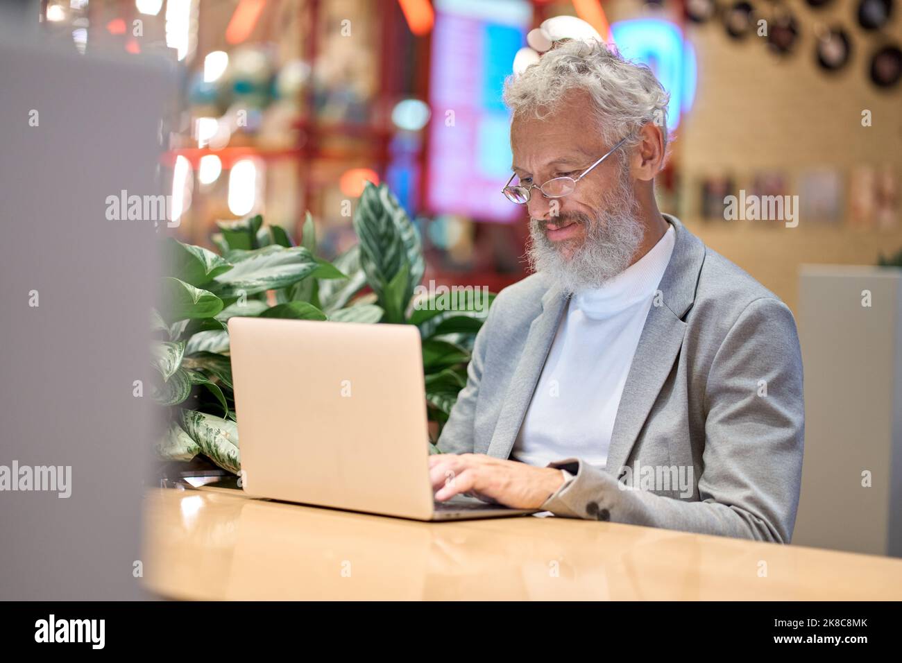 Sorridendo un vecchio uomo d'affari senior che utilizza un notebook che lavora tardi sul computer. Foto Stock