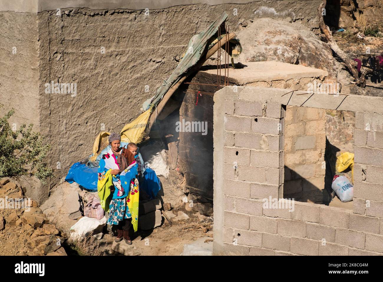 La madre berbera porta un bambino alle spalle in un villaggio nelle montagne dell'Alto Atlante, nella valle di Ourika, in Marocco, in Nord Africa Foto Stock