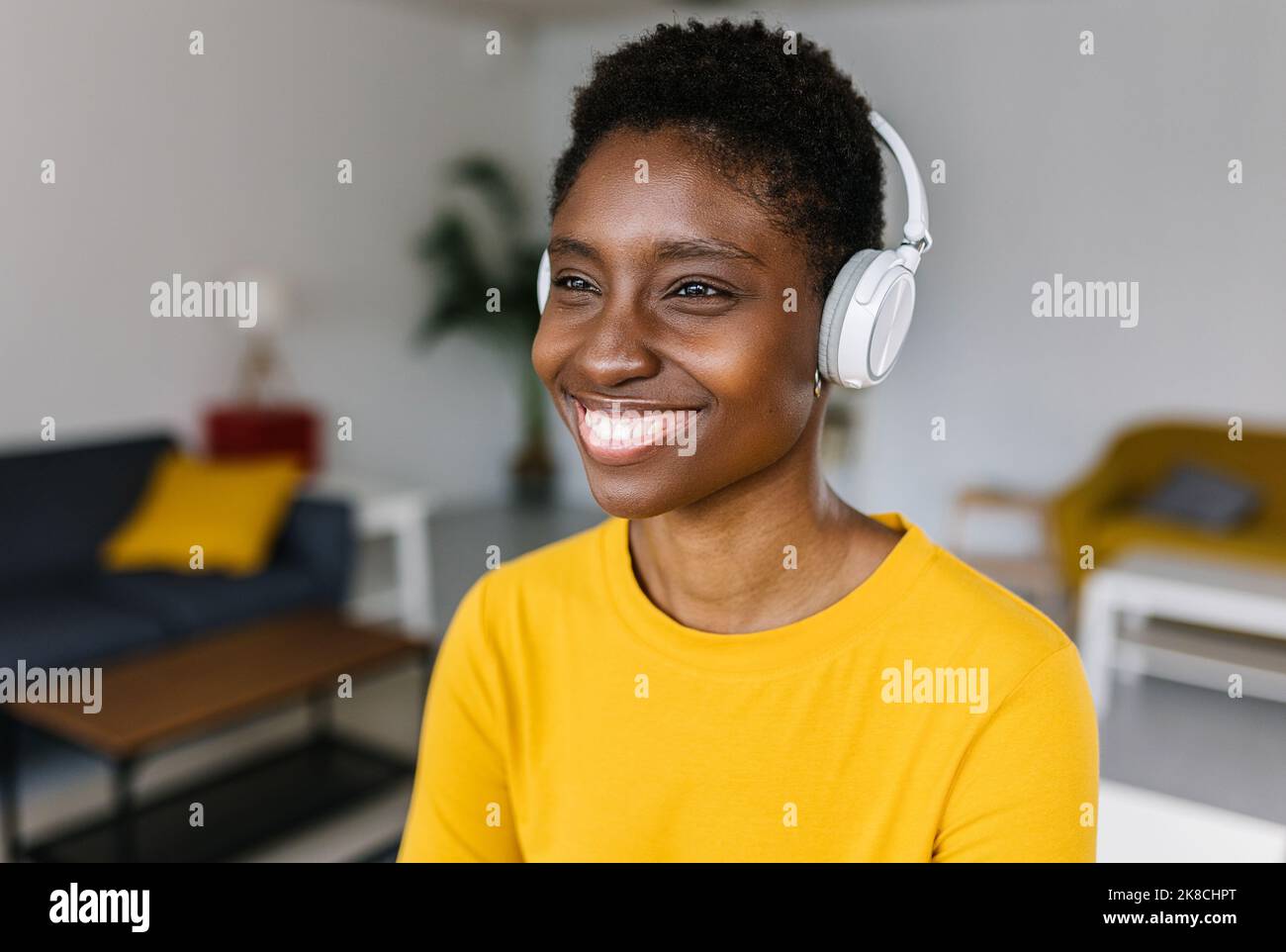 Ritratto di giovane donna africana sognante che ascolta musica con le cuffie Foto Stock