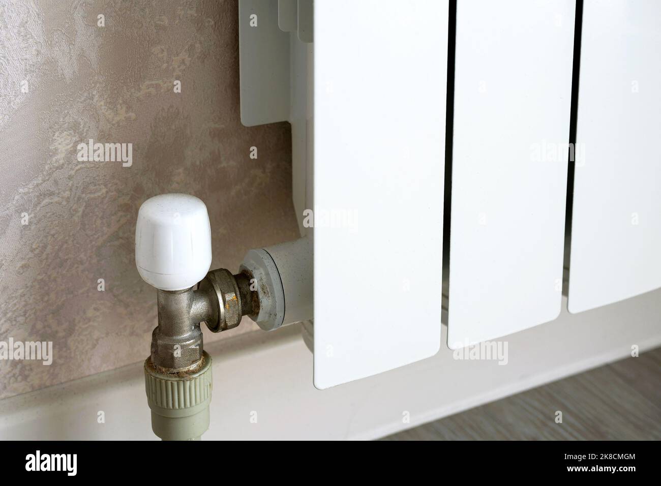 Radiatore di riscaldamento con termostato a parete, scaldabagno in metallo bianco in camera. Concetto di calore, crisi energetica, risparmio, radiatore contemporaneo Foto Stock