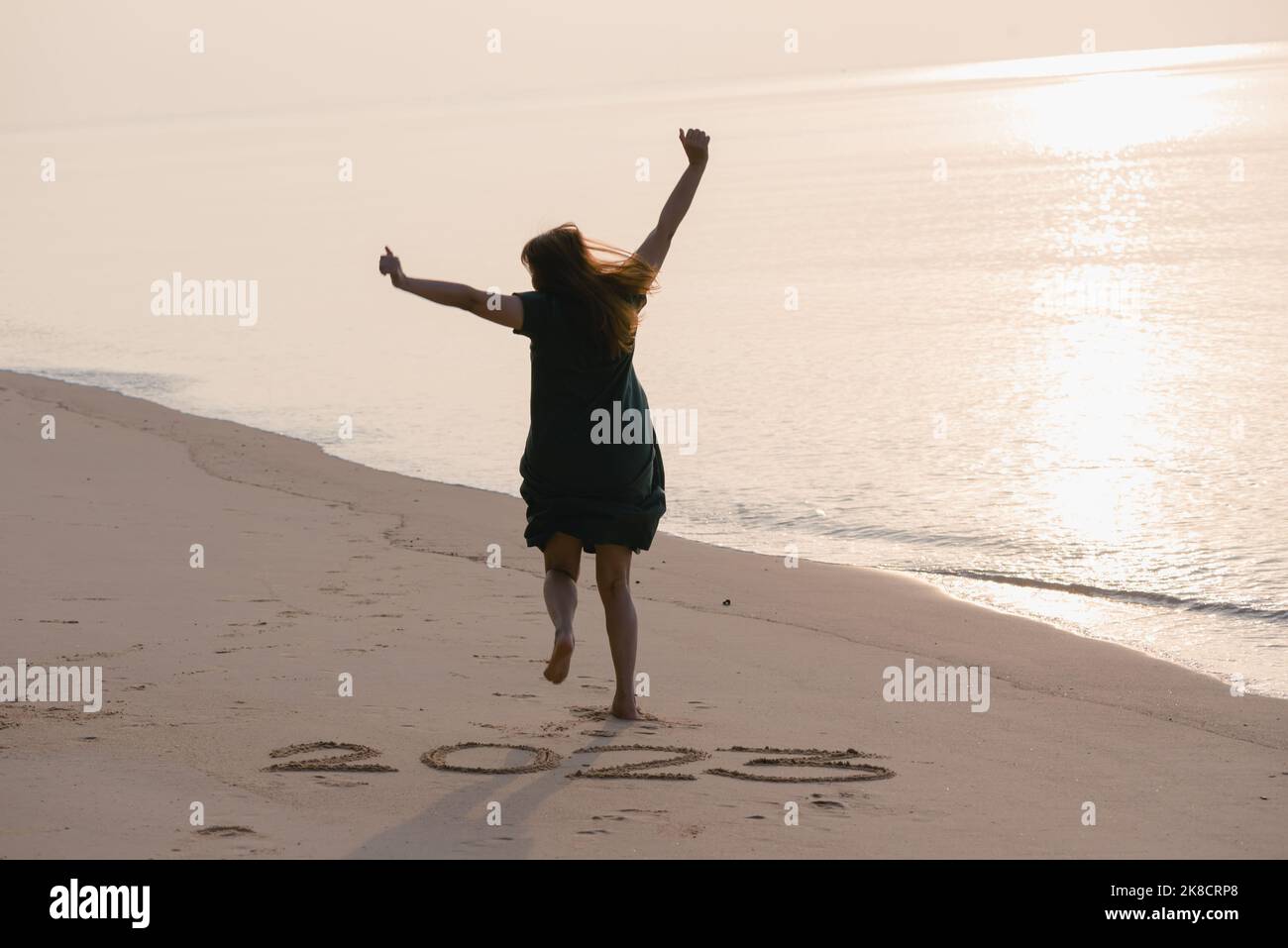 2023 Felice anno nuovo, giovane donna sana che corre e salta sulla spiaggia all'alba, assistenza sanitaria, assicurazione sanitaria, concetto di vita sana, copia spazio Foto Stock