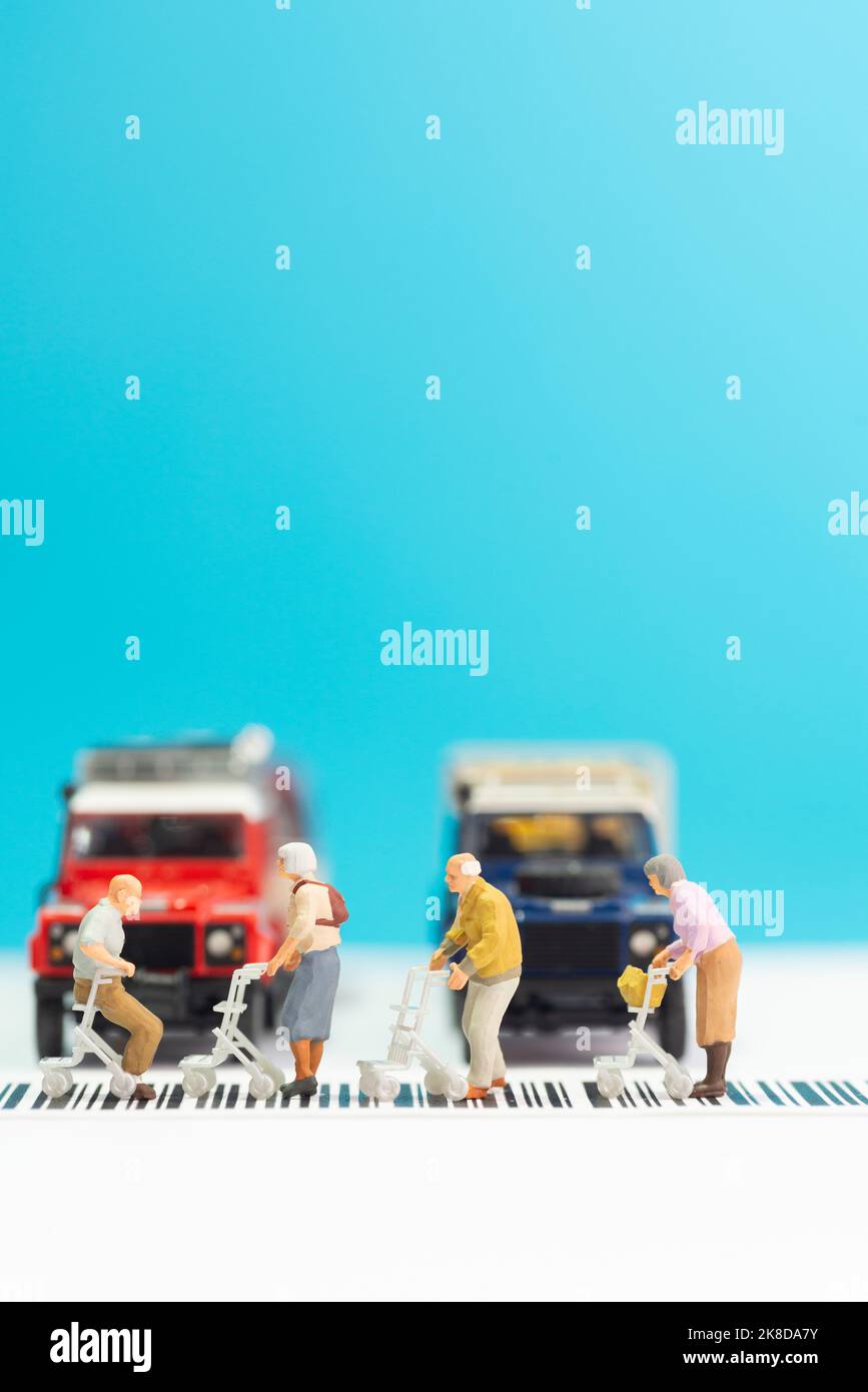 Giocattoli in miniatura un gruppo di persone anziane con sedia a rotelle che attraversa una strada - concetto di sicurezza stradale per gli anziani. Foto Stock