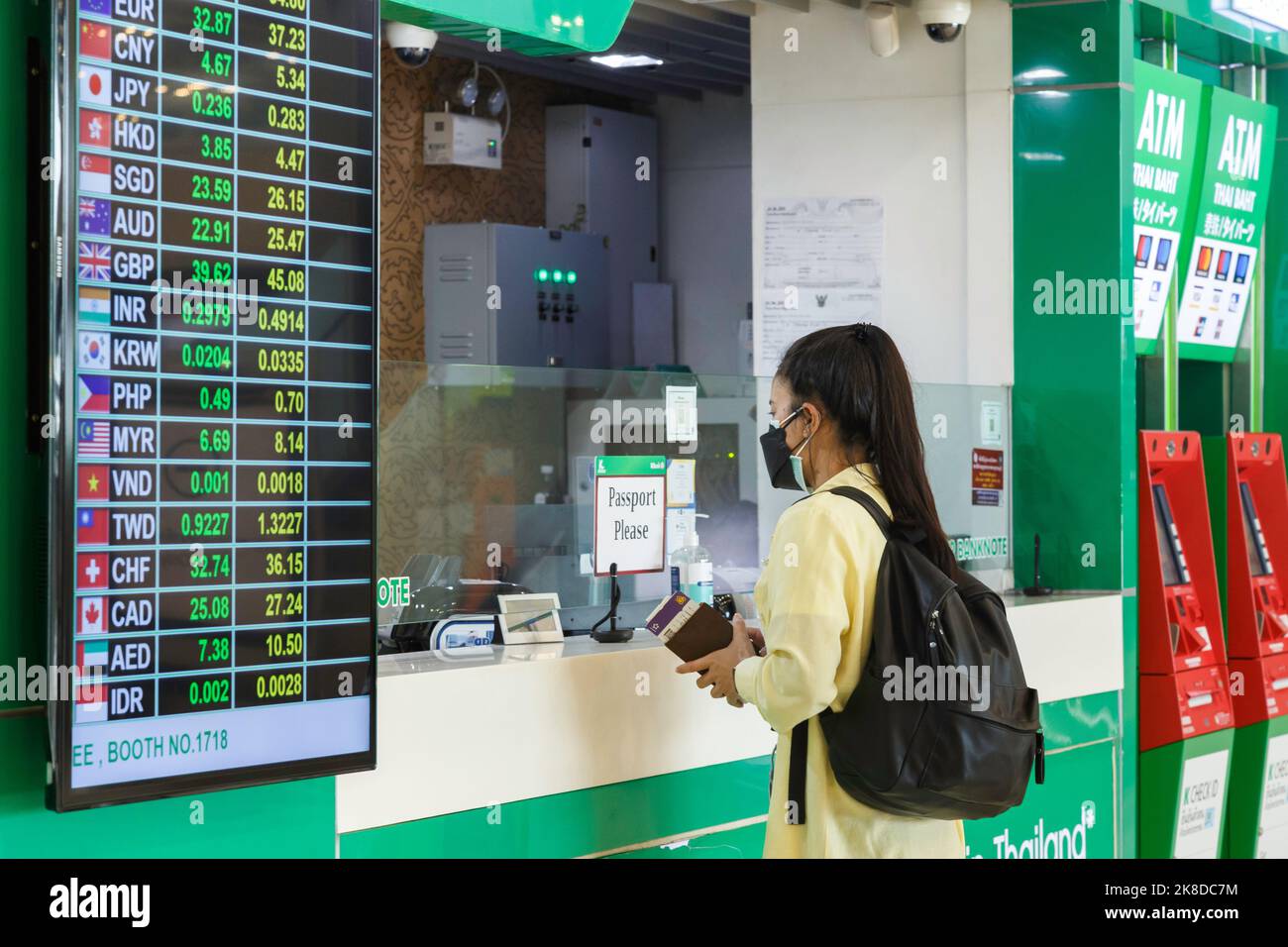 Bangkok, Thailandia - 26 ottobre 2022 : viaggiatore asiatico in banca sportello di cambio valuta presso l'aeroporto suvarnabhumi con visualizzazione del tasso di cambio valuta Foto Stock