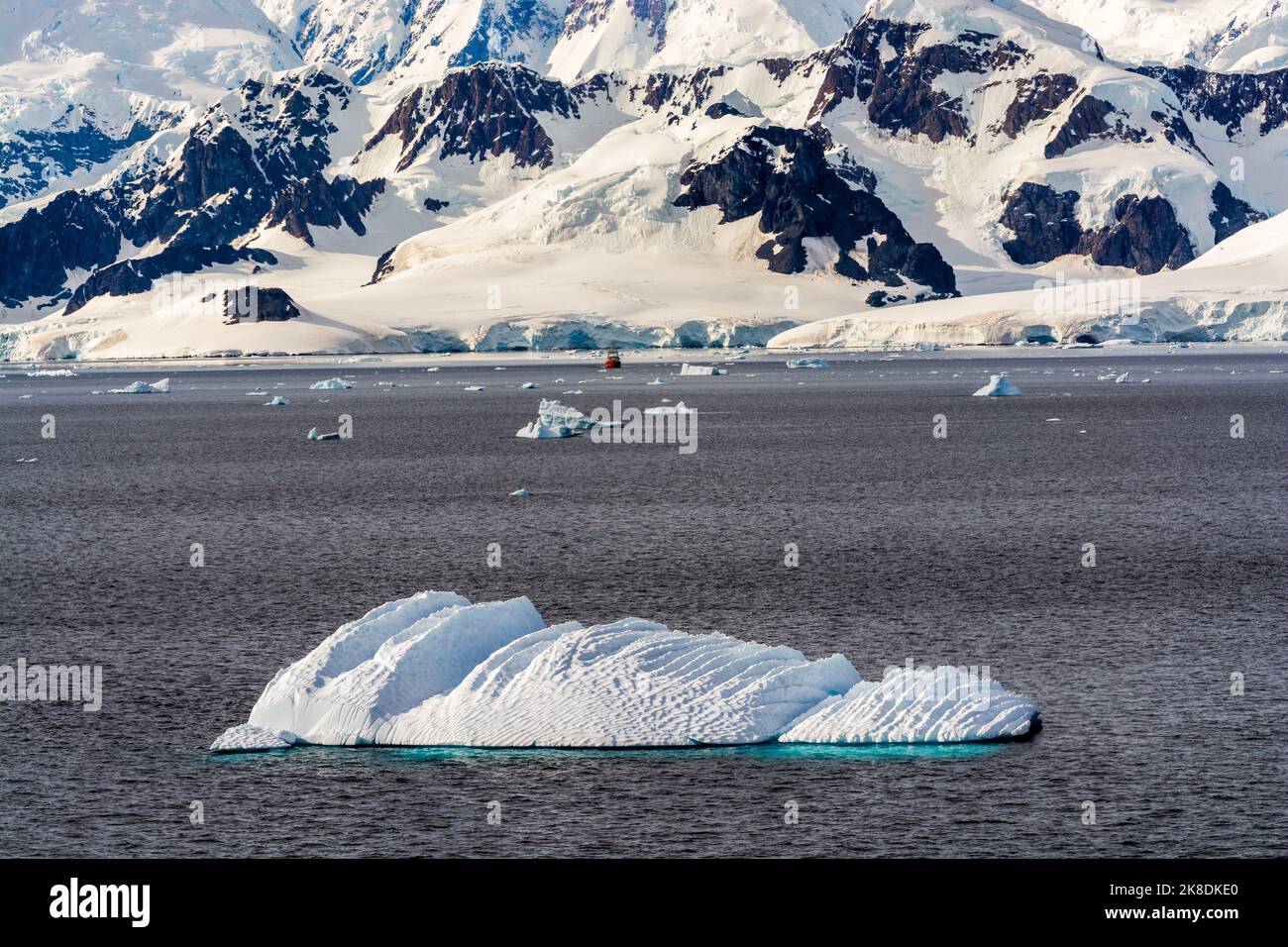 iceberg nello stretto di gerlache con porto paradiso (baia) e penisola antartica sullo sfondo. nave della prefettura argentina al centro. antartide Foto Stock