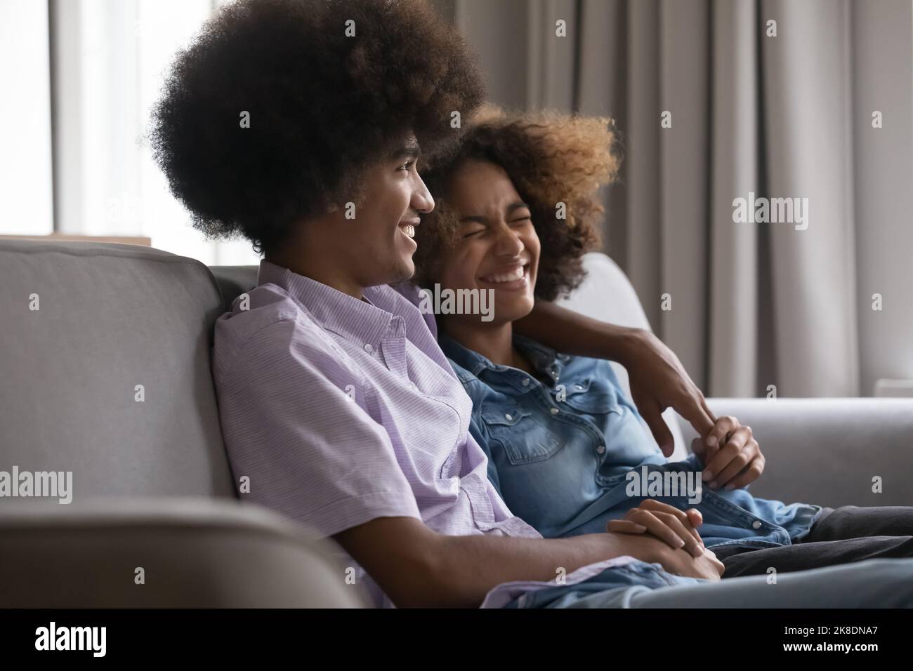 Ridendo giovane coppia africana abbracciando seduti sul divano Foto Stock