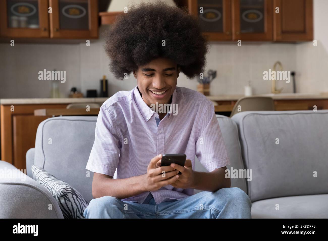 Un simpatico ragazzo africano utilizza lo smartphone moderno a casa Foto Stock