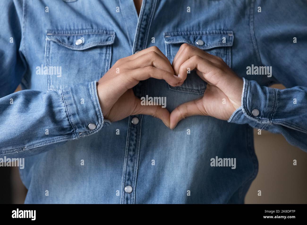 Ragazza ripresa tagliata che mostra il simbolo del cuore con le dita unite Foto Stock