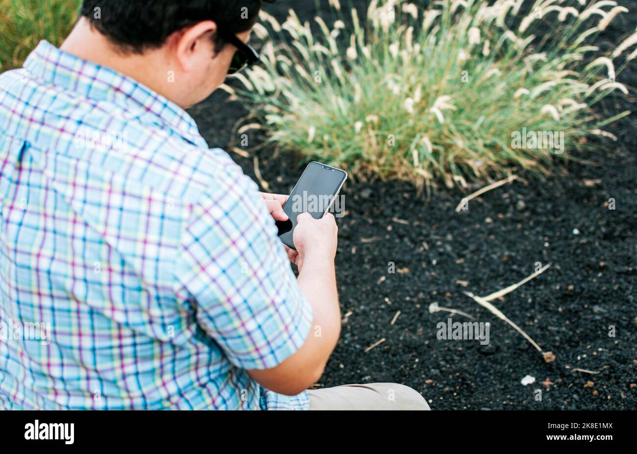 Vista di un uomo con il telefono delle cellule in mano, primo piano di un uomo utilizzando il telefono delle cellule e mostrando lo schermo, giovane uomo seduto con il telefono delle cellule che mostra lo schermo vuoto Foto Stock