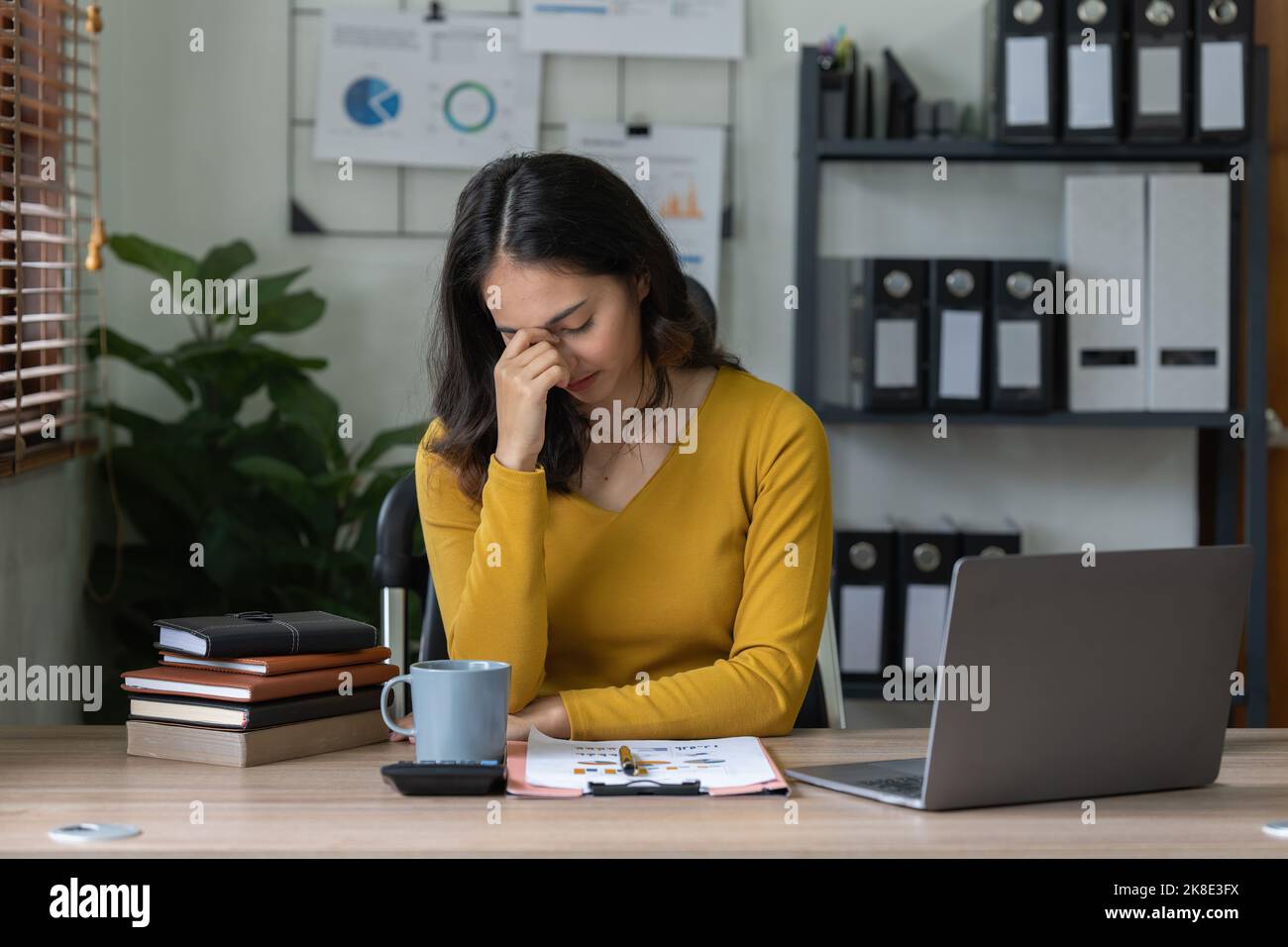 Stressata donna asiatica d'affari si preoccupano di molti documenti sulla scrivania in ufficio Foto Stock