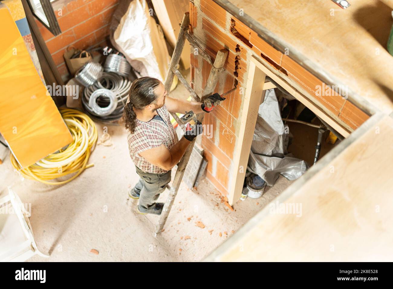 Uomo forte che usa le scale per riparare una casa Foto Stock