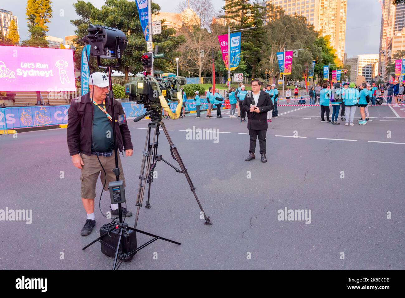 Un reporter e cameraman si sono allestiti per una croce dal vivo al Morning Show su Chanel 7 a Sydney prima dell'inizio della gara City to Surf a Bondi Foto Stock