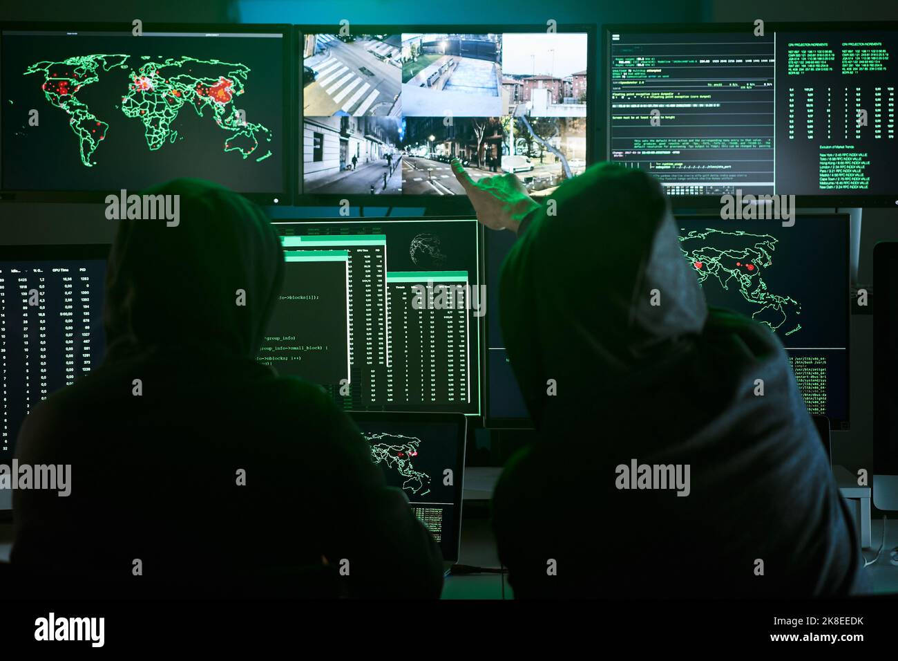 Vista posteriore di irriconoscibile squadra criminale Hacker puntare telecamere di sicurezza sullo schermo utilizzando il computer per organizzare massiccia violazione di dati attacco Foto Stock