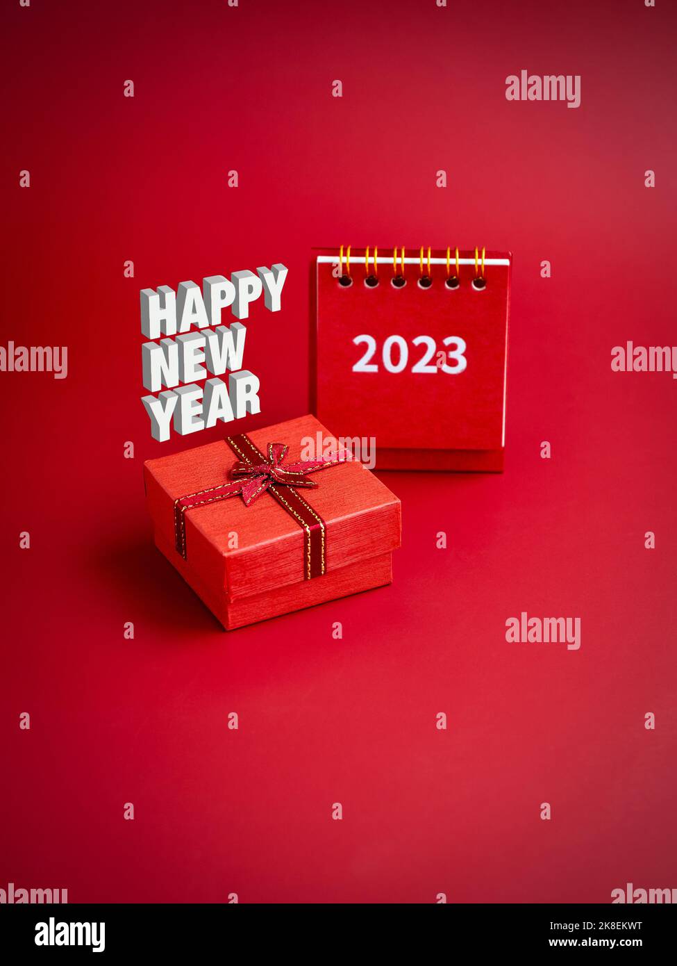 felice anno nuovo 3D, testo fluttuante sulla piccola confezione regalo regalo rossa con 2023 anno di calendario da tavolo su sfondo rosso, stile verticale. Banner regalo speciale Foto Stock