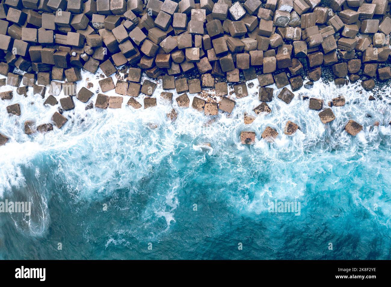 Vista aerea del drone di un Breakwater in cemento. Breakwater nel mare. Acque blu dell'Oceano Atlantico dall'alto. Foto Stock