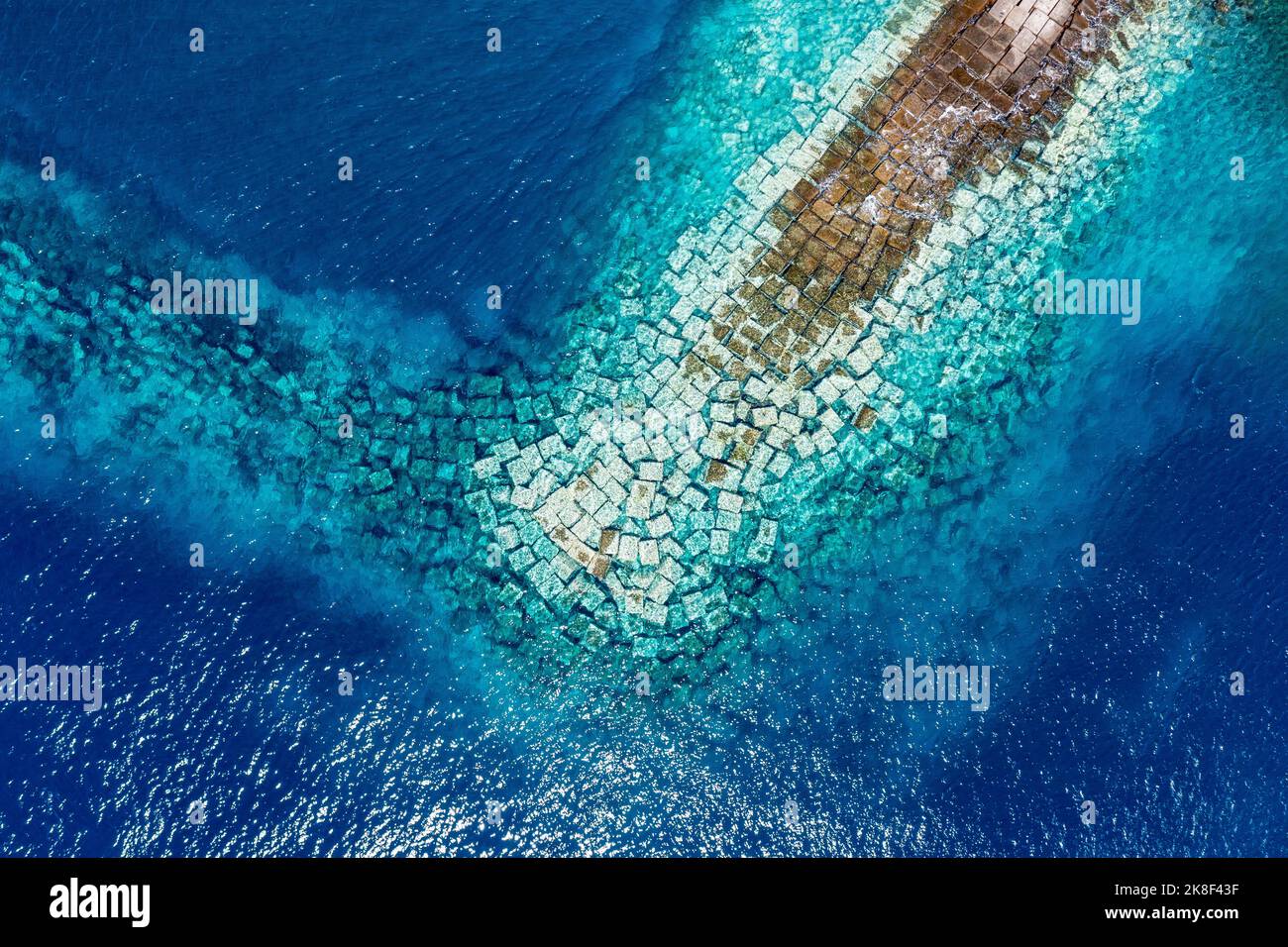 Vista aerea del drone di un Breakwater in cemento. Breakwater nel mare. Acque blu dell'Oceano Atlantico dall'alto. Foto Stock