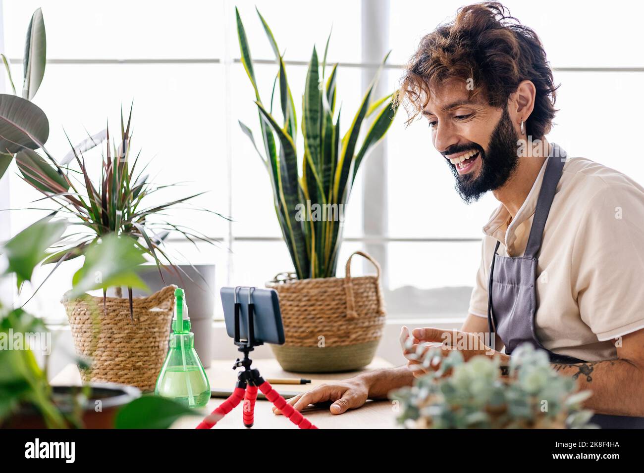 Uomo felice con smartphone su treppiede presso il negozio di impianti Foto Stock