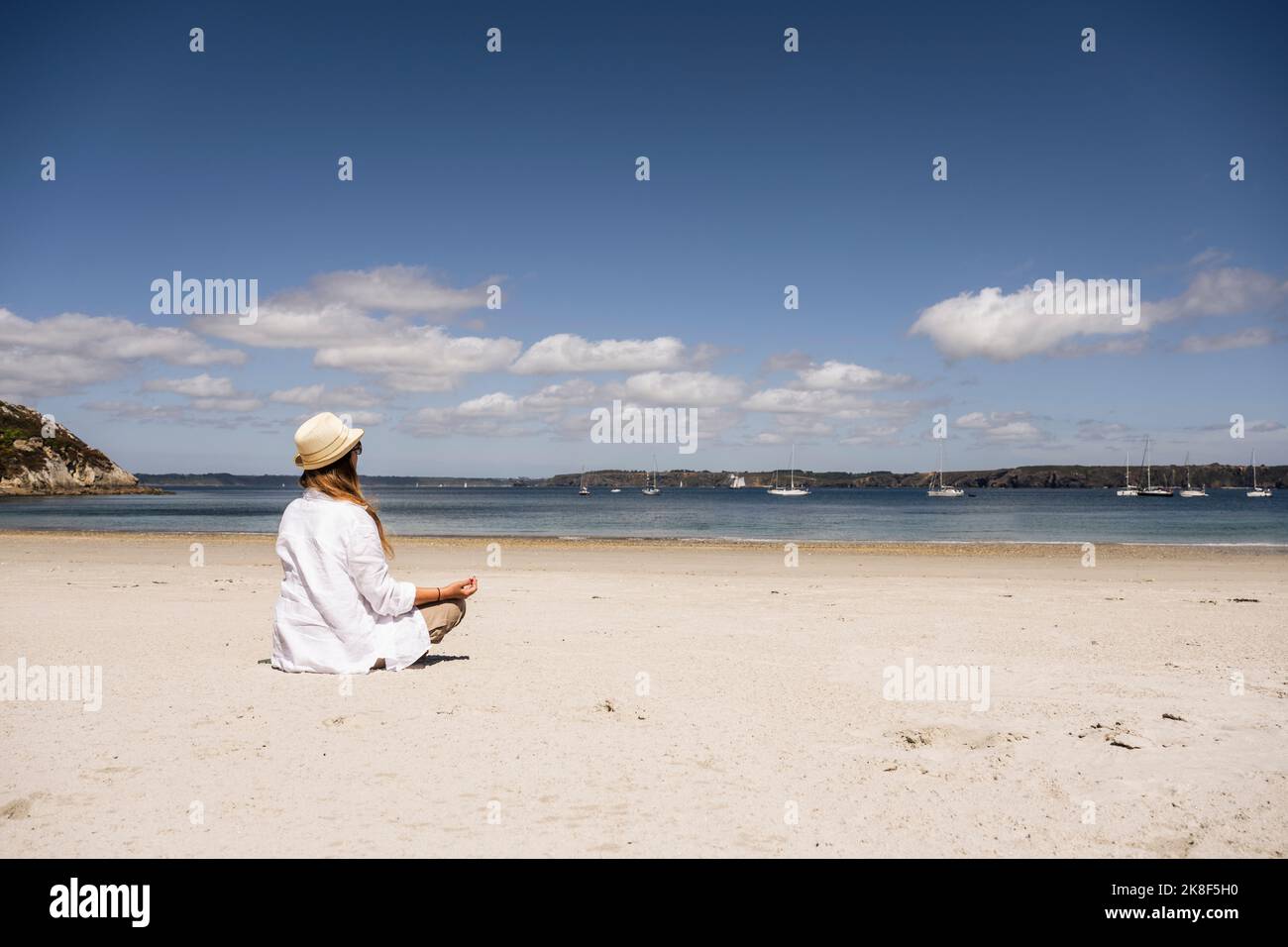 Donna matura che pratica meditazione in spiaggia Foto Stock