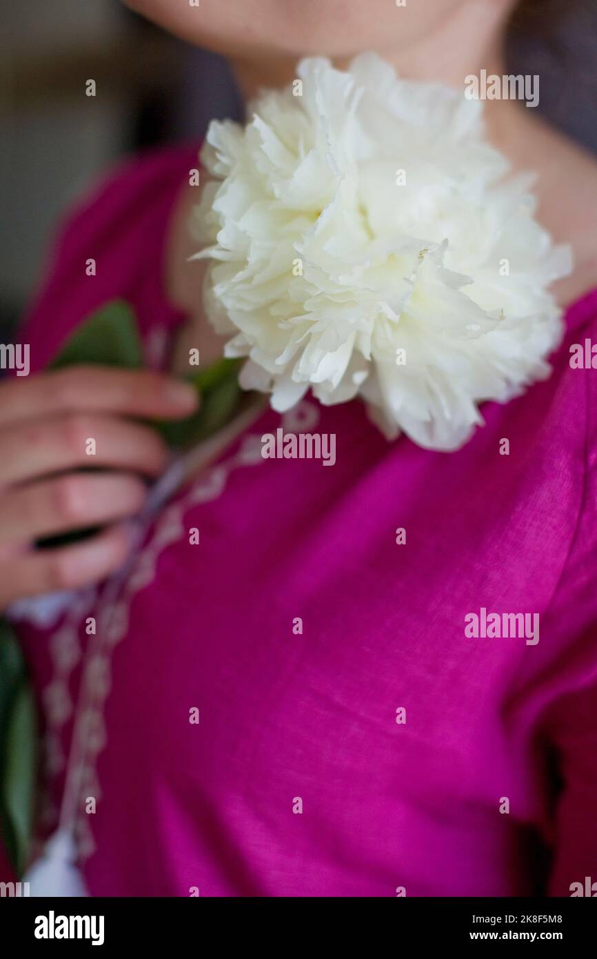 Donna con vestito rosa Vyshyvanka che tiene fiore di peonia bianca Foto Stock