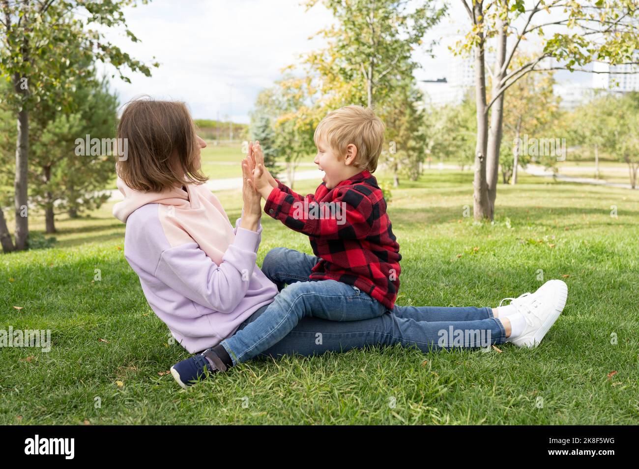 Madre con figlio che gioca a gioco di clapping al parco Foto Stock
