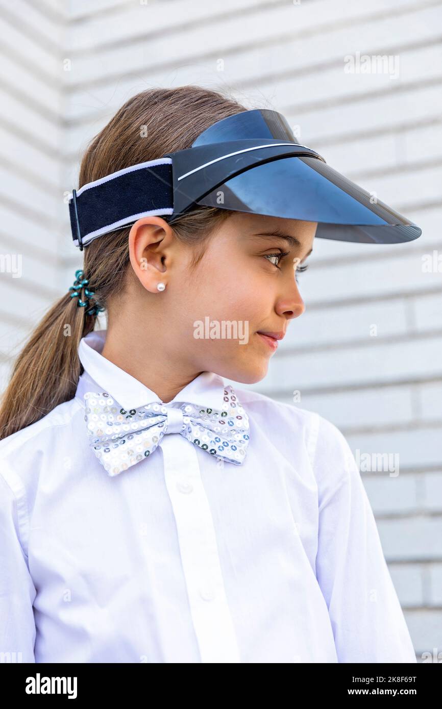 Ragazza con capelli marroni che indossa visiera parasole e cravatta ad arco Foto Stock