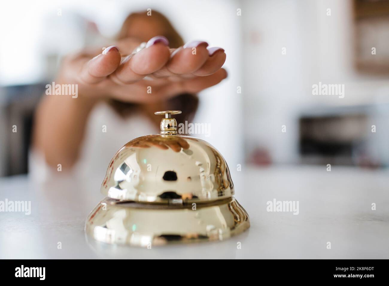 Mano di una donna d'affari che suona il servizio di facchinaggio al ristorante Foto Stock
