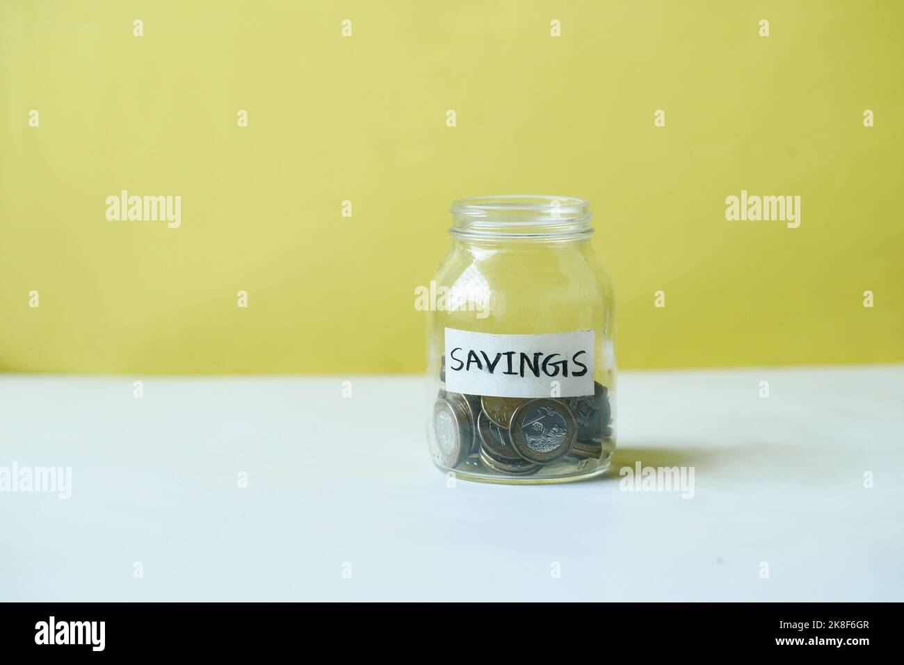 vasetto di risparmio monete e calcolatrice sul tavolo Foto Stock