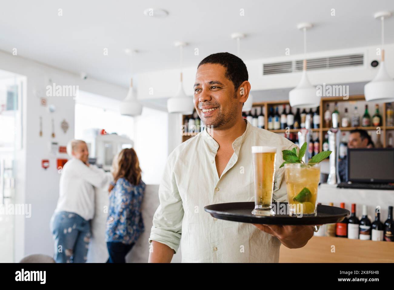 Buon cameriere che serve bevande al ristorante Foto Stock