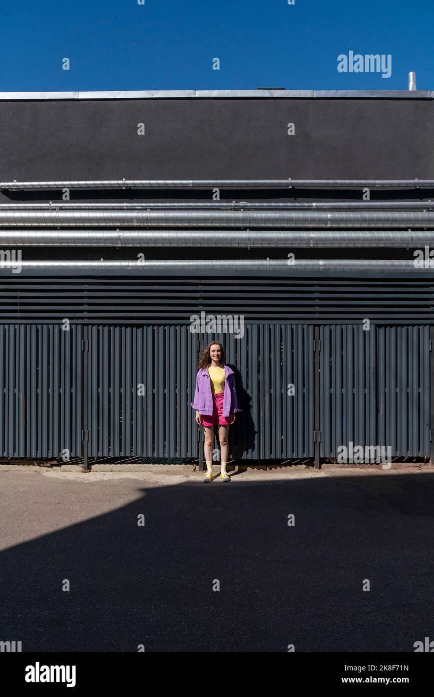 Giovane donna in piedi di fronte al muro nero Foto Stock