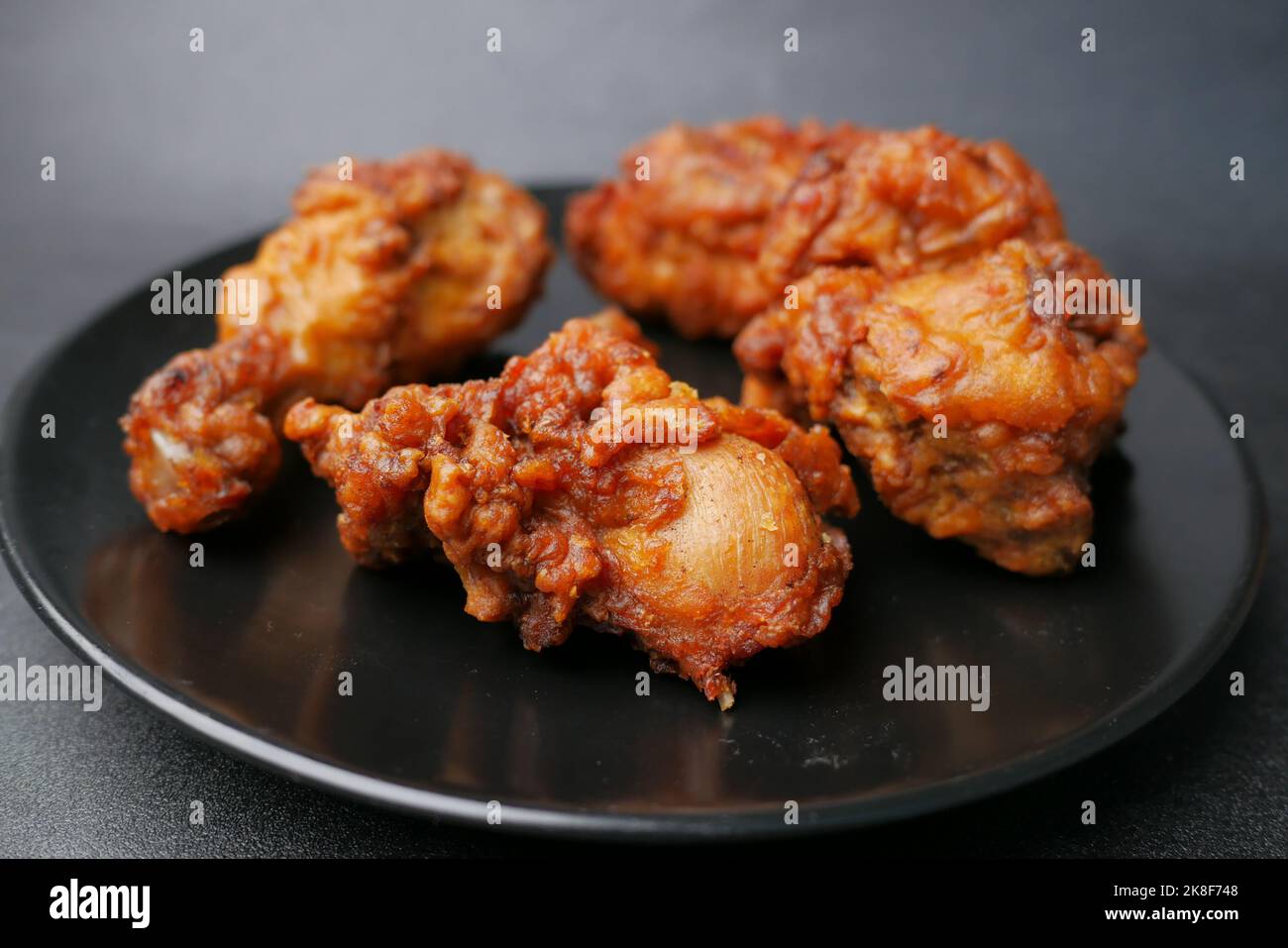 filetti di pollo fritti su piatto su sfondo nero Foto Stock