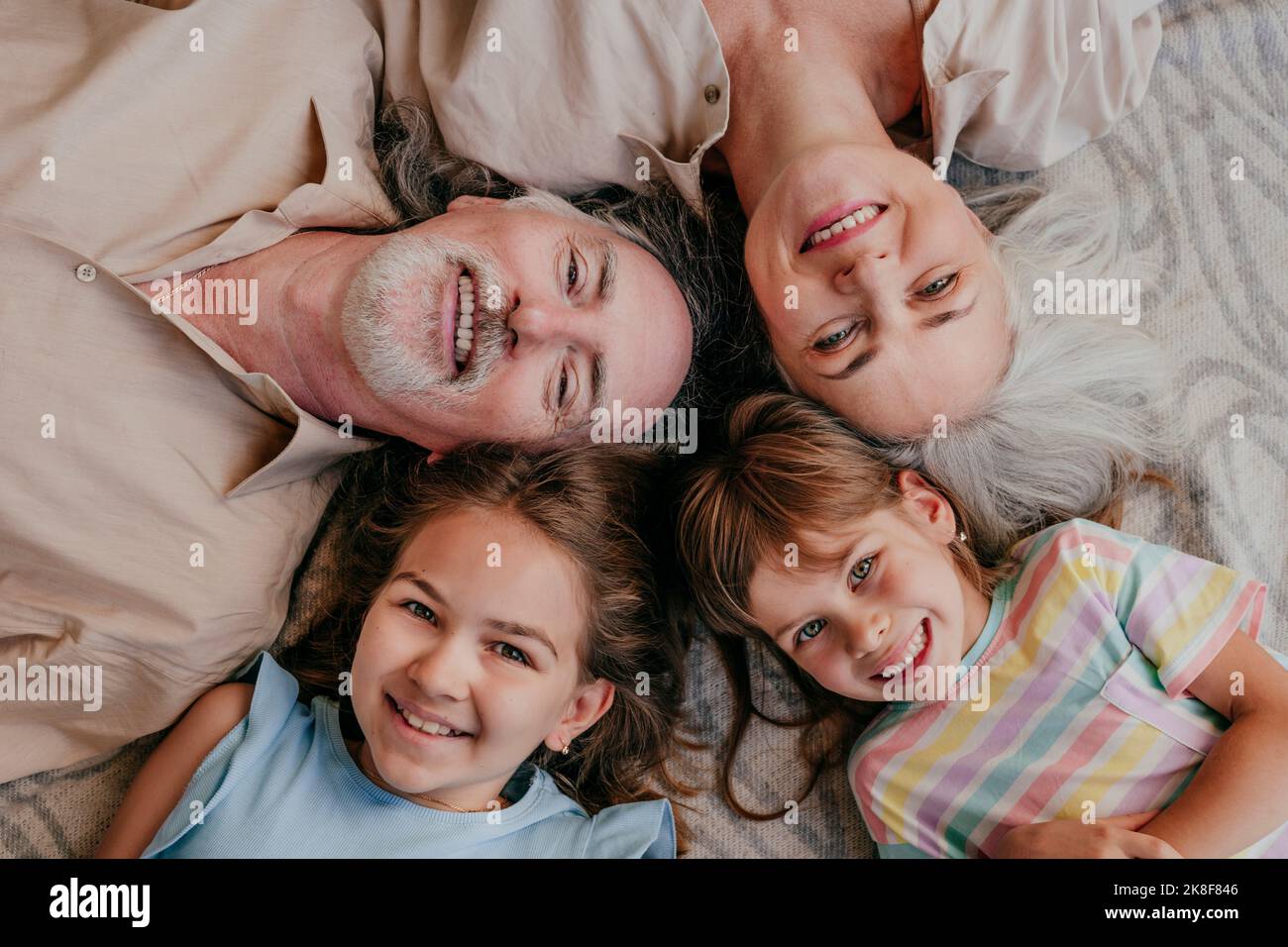 Nonni e nipoti felici sdraiati con la testa in cerchio a casa Foto Stock