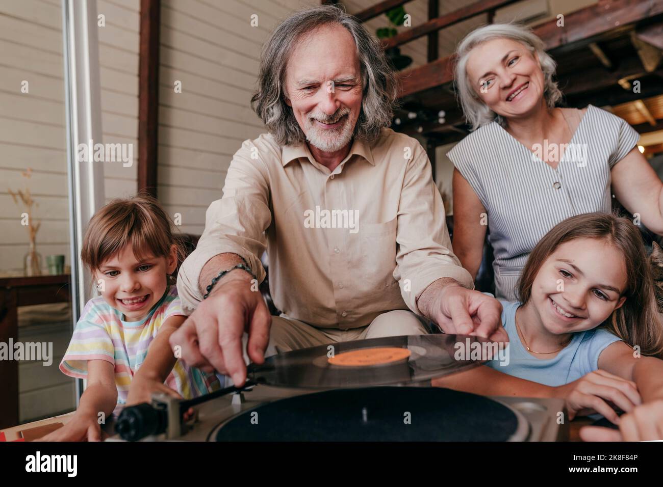 Nonno sorridente che cambia record sul giradischi da nipoti a casa Foto Stock