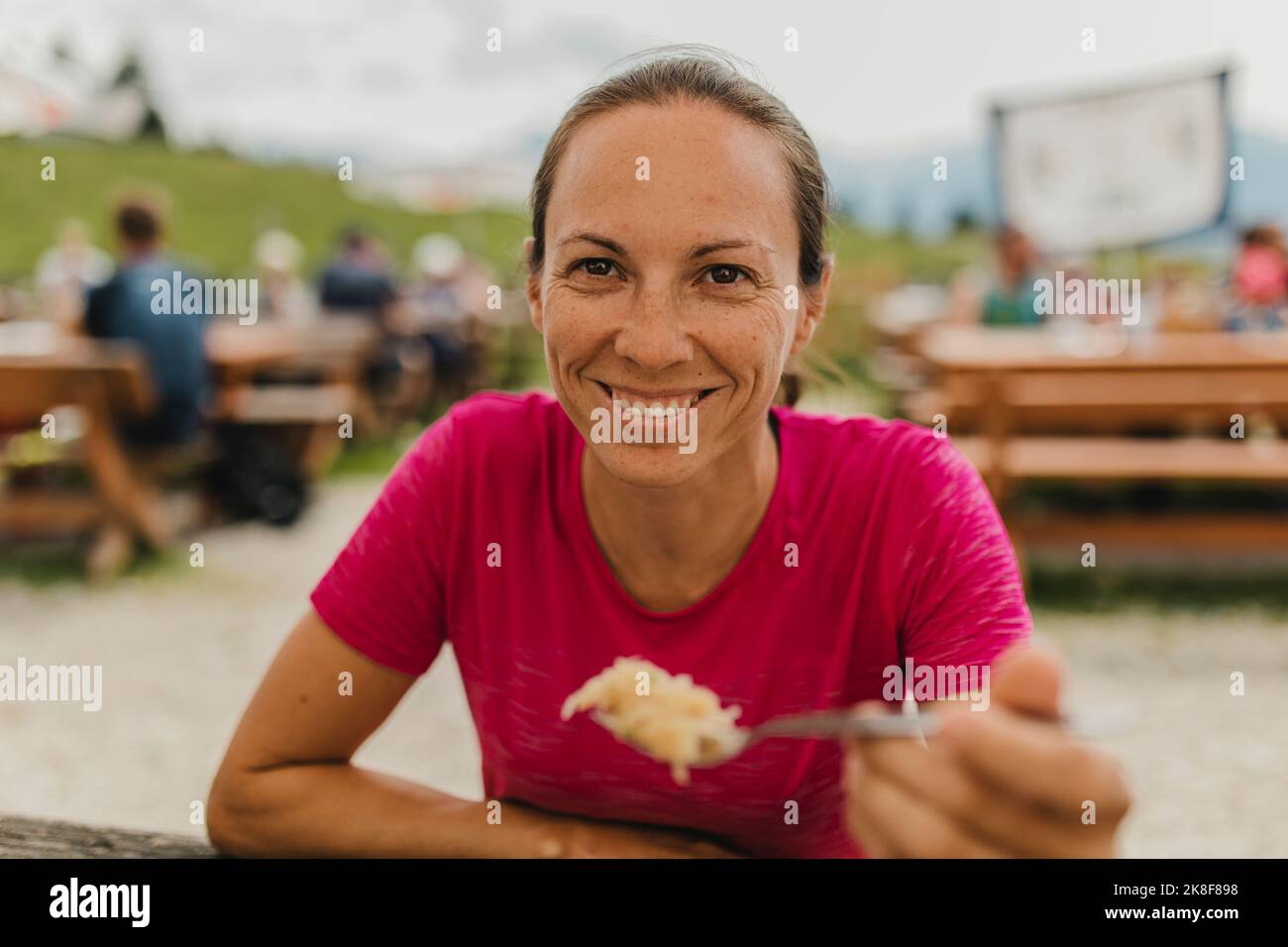 Un escursionista sorridente che mostra il cucchiaio pieno di cibo Foto Stock