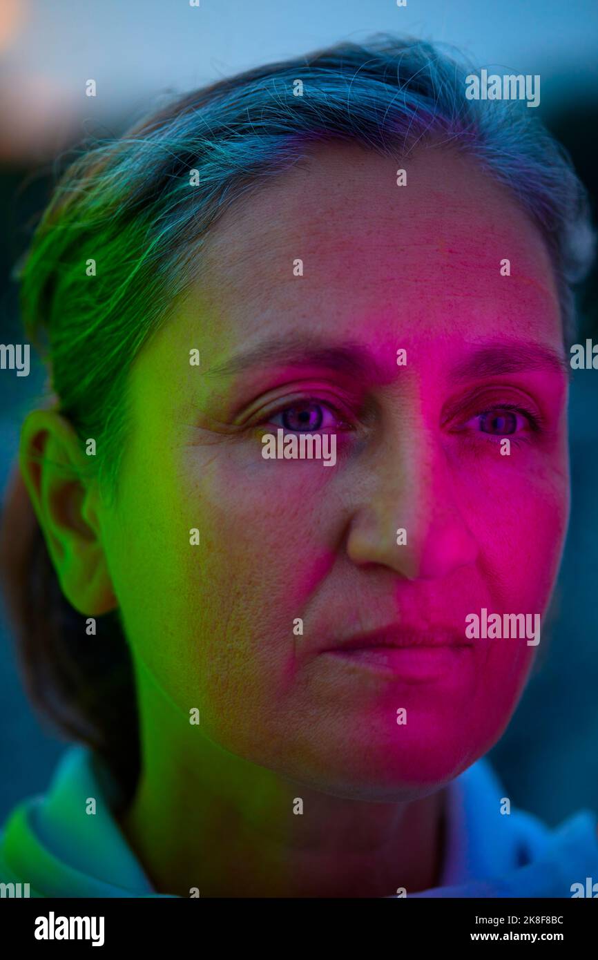 Donna premurosa con riflesso di luce multicolore sul viso Foto Stock