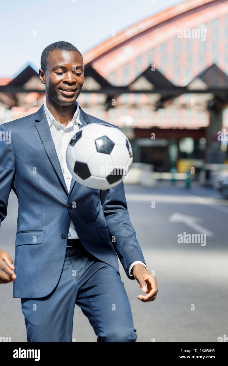 Buon uomo d'affari che gioca con la palla di calcio nella giornata di sole Foto Stock
