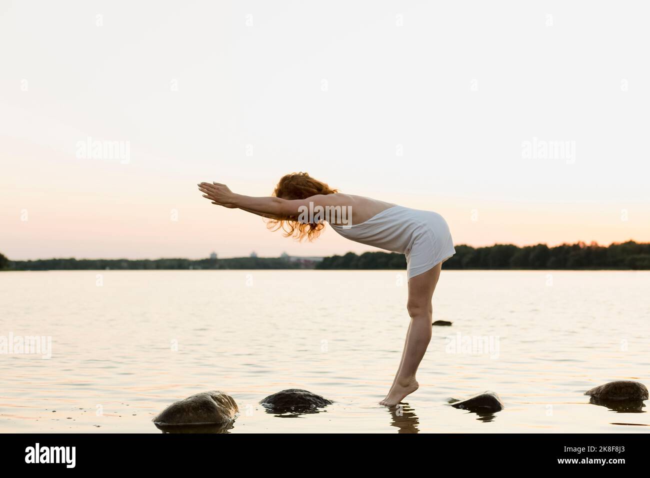 Donna con vestito bianco esercizio al lago Foto Stock