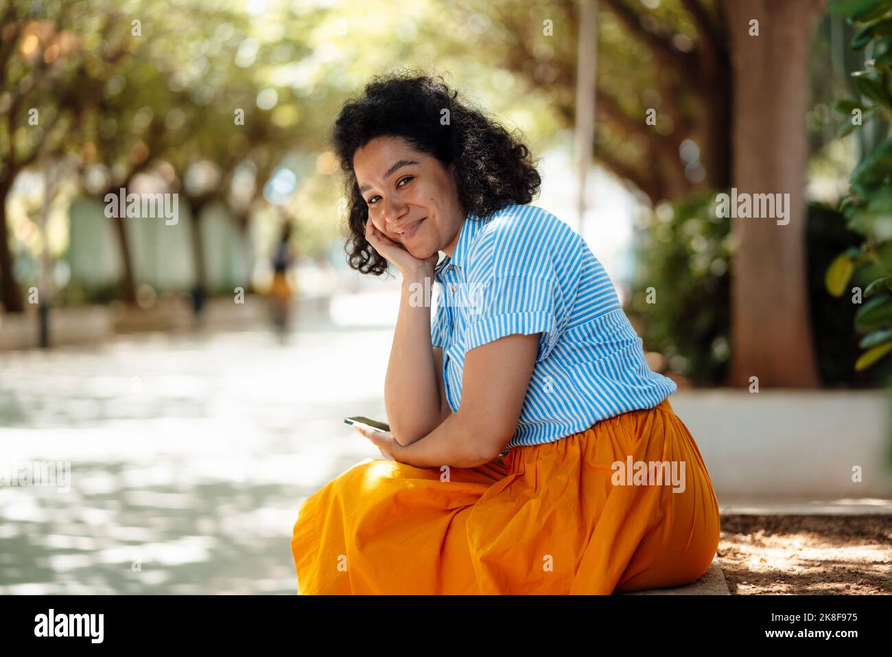 Donna sorridente appoggiata al gomito che tiene lo smartphone Foto Stock