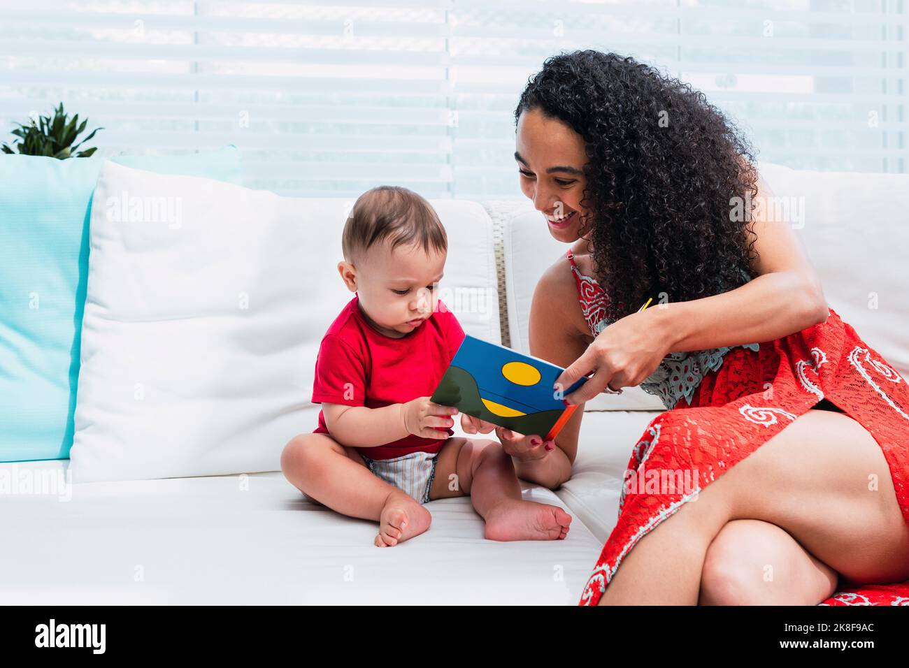 Felice madre che legge il libro di storia a figlio seduto sul divano a casa Foto Stock