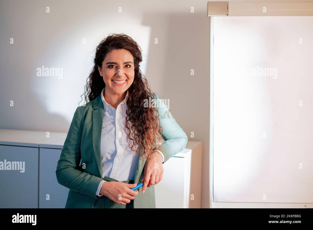 Donna d'affari sorridente appoggiata al gabinetto sul posto di lavoro Foto Stock