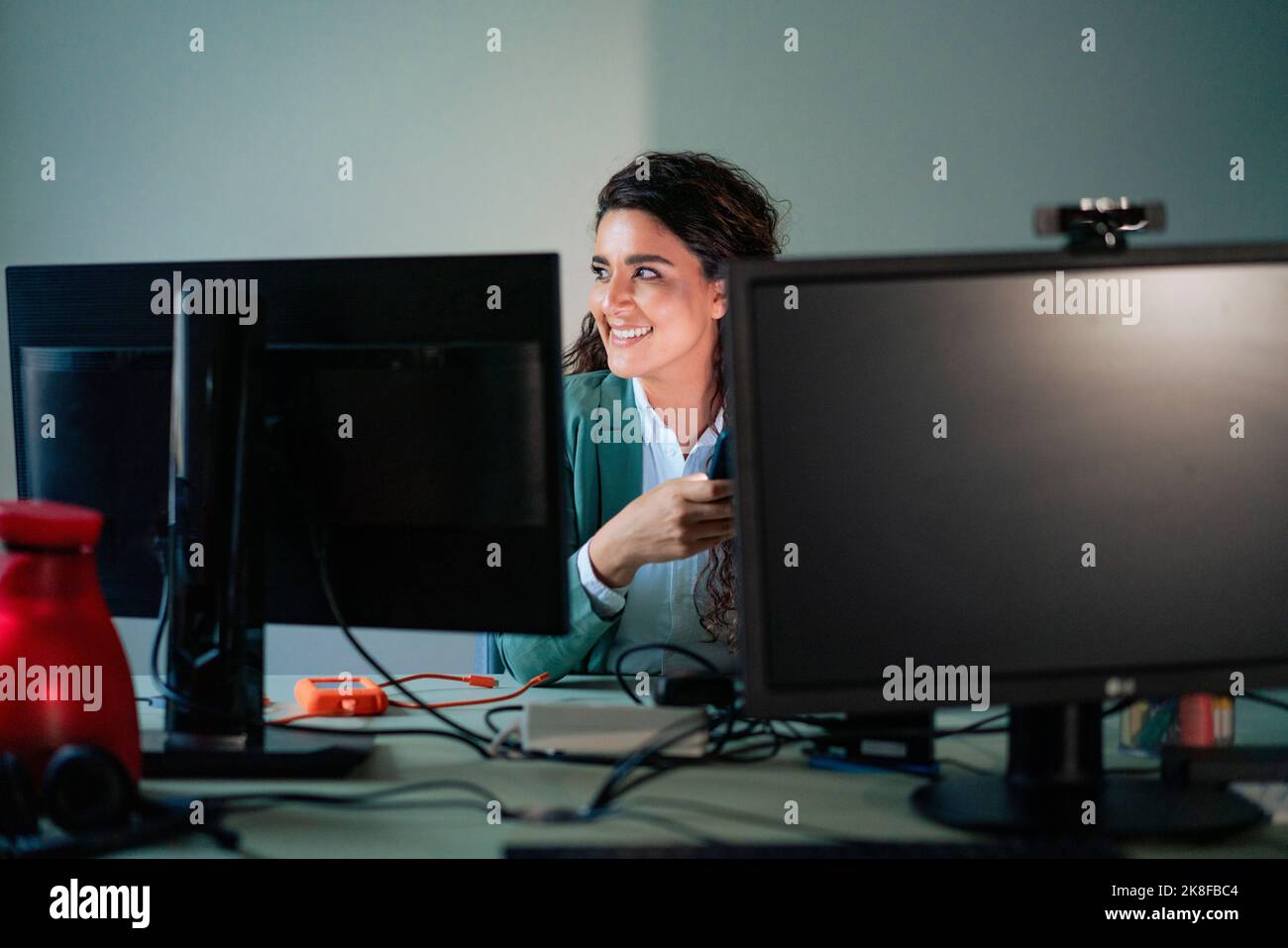 Donna d'affari sorridente seduta alla scrivania del computer Foto Stock