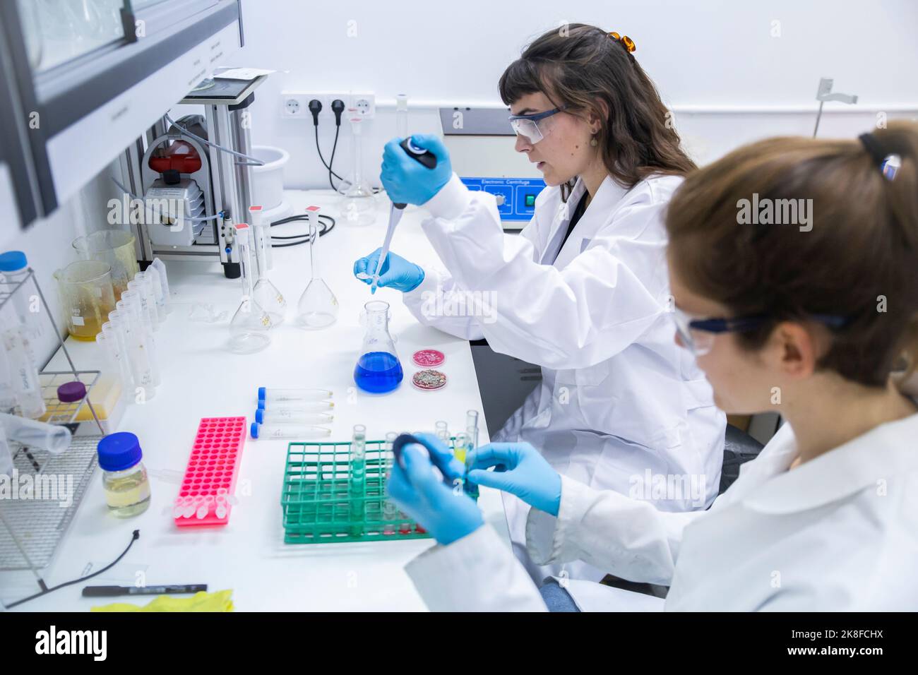 Scienziati che sperimentano con sostanze chimiche sul tavolo in laboratorio Foto Stock