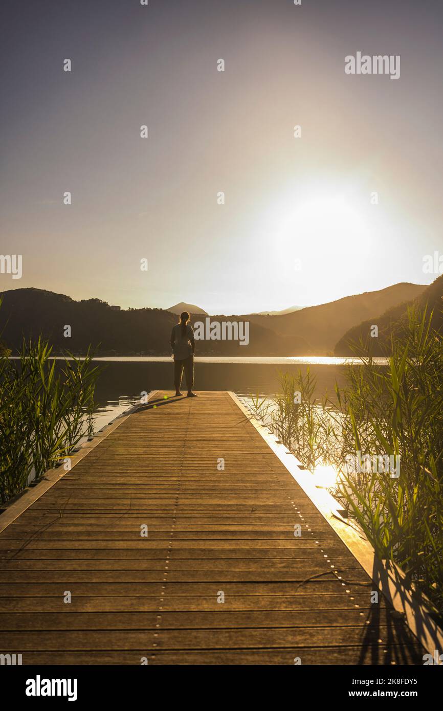Donna sul molo vicino al lago e alle montagne Foto Stock
