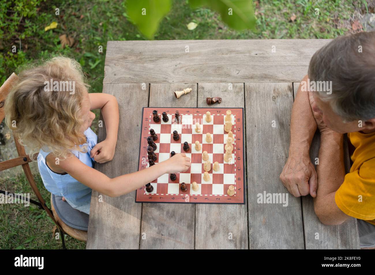 Nipote e nonno giocano a scacchiera in giardino Foto Stock