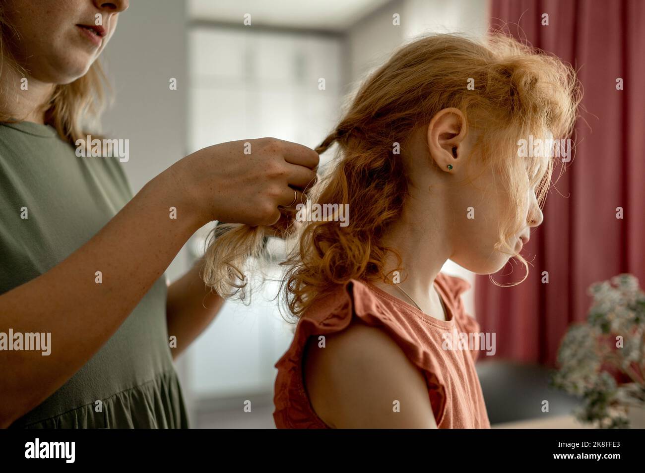 Madre intrecciando capelli di figlia a casa Foto Stock