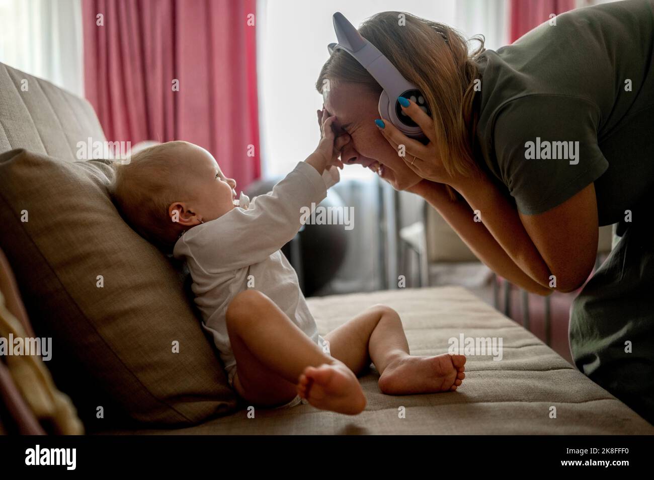 Mamma giocosa che indossa le cuffie che gioca con la figlia Foto Stock