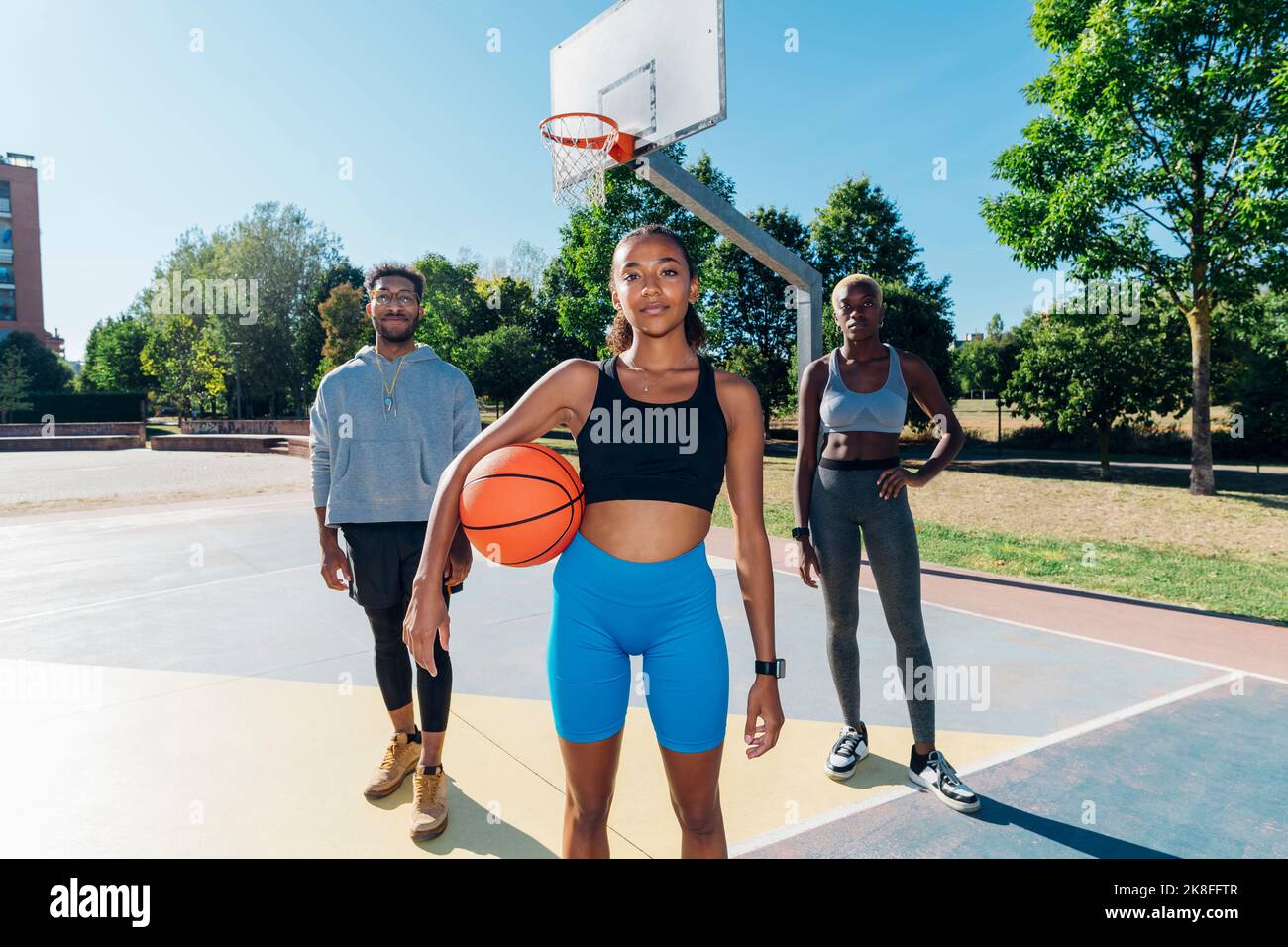 Giocatori di pallacanestro fiduciosi in campo sportivo nelle giornate di sole Foto Stock