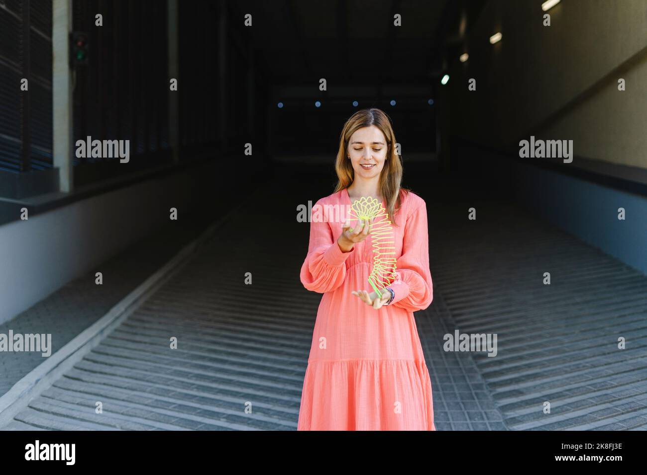 Donna sorridente che gioca con il giocattolo della molla elicoidale Foto Stock